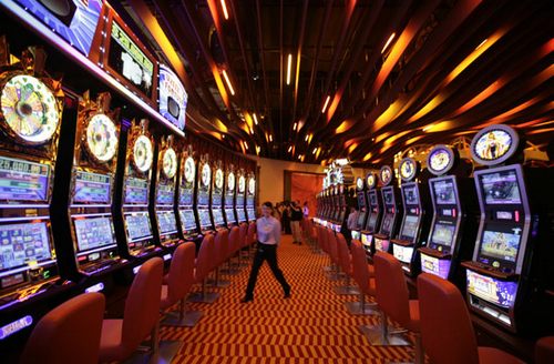 An attendant walks between rows of slot machines inside the Resorts World Sentosa casino on Singapore's Sentosa Island